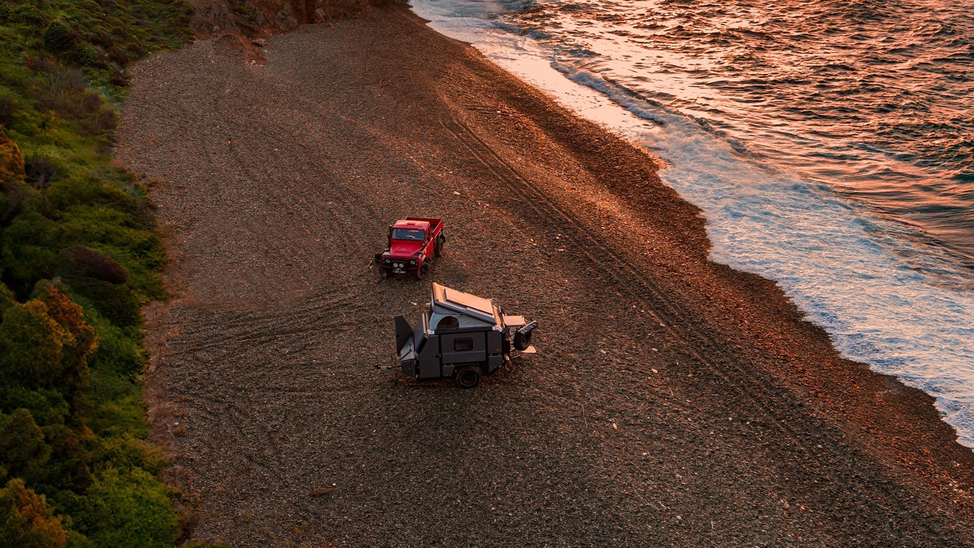 Off-grid caravan setup on a remote beach during sunset with lithium battery and solar power system